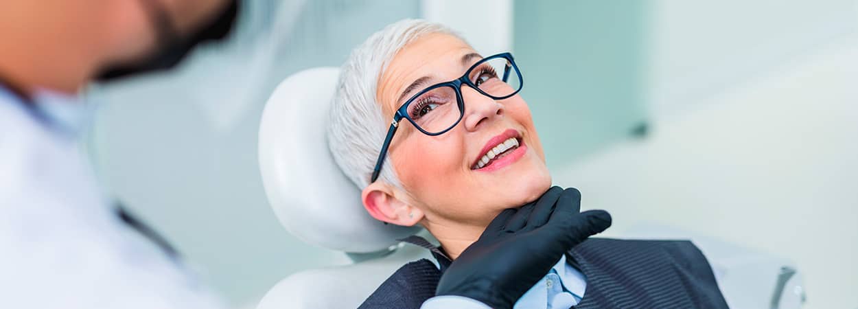 femme sur une chaise qui regarde et sourie au dentiste